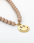 Taupe kralenketting met gouden stainless steel smiley