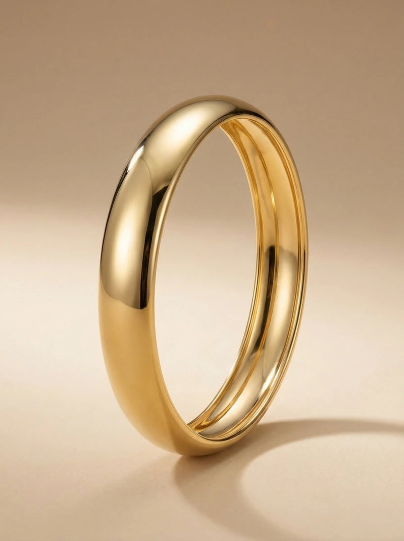 Brede goudkleurige Bold Affair bangle van stainless steel met een glad, afgerond oppervlak.