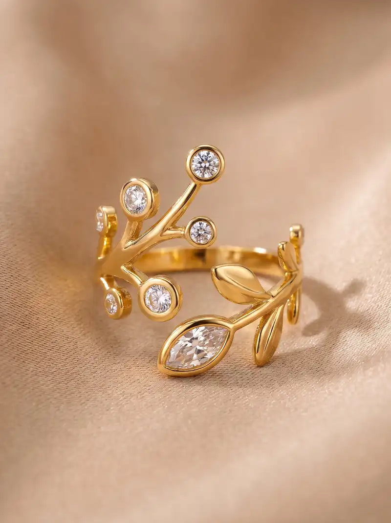 Goudkleurige verstelbare Crystal Garden ring van stainless steel met takjes, goudkleurige blaadjes en ronde en langwerpige transparante steentjes.