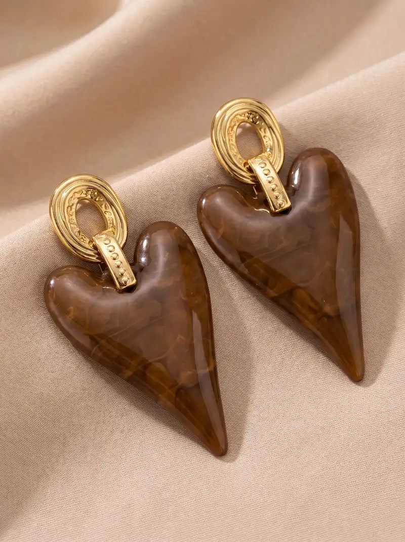 Heart Couture oorbellen met grote glanzende bruine hartvormige hangers en goudkleurige stainless steel oorstekers.