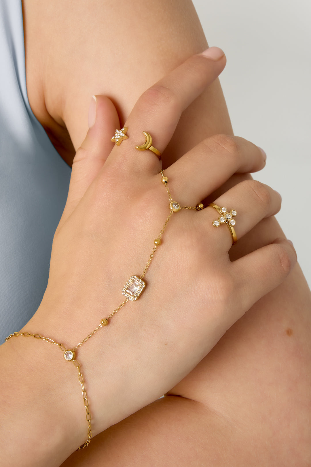 Goudkleurige stainless steel hand chain met heldere steentjes en rechthoekige steen